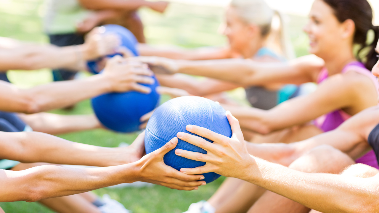 Participants passing a medicine ball between each other as part of a bootcamp class